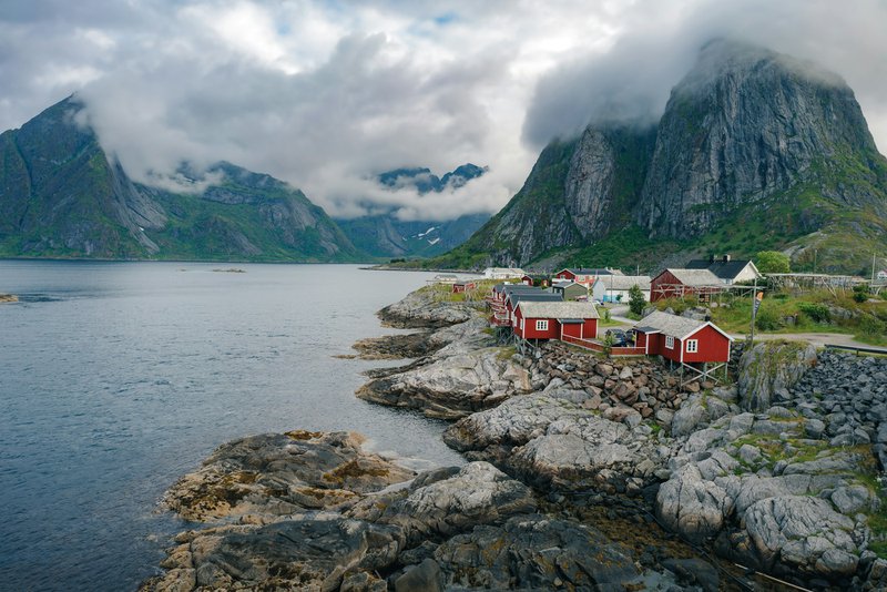 A small village on a rocky shore with mountains in the background